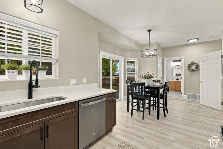 Kitchen featuring dark wood-finish cabinetry, quartz countertops, a stainless steel dishwasher, wood-finish flooring, and a sliding glass door