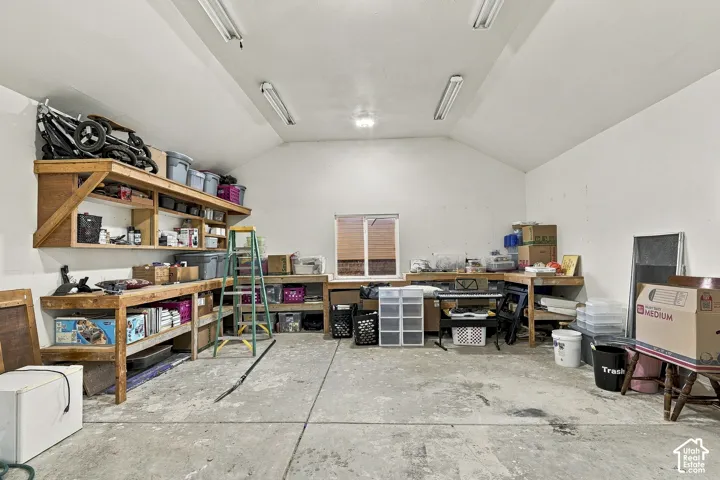 Garage space featuring concrete flooring, built-in wooden shelving, a work surface, and overhead lighting