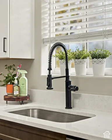 Undermount stainless steel sink featuring a matte black industrial-style pull-down faucet and light-toned solid surface countertop