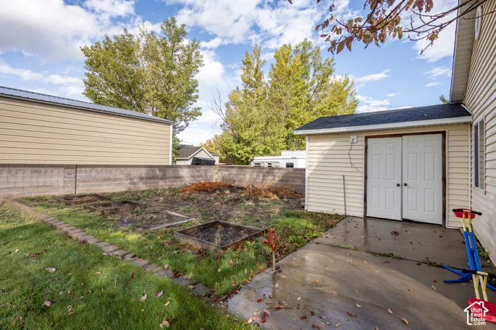Exterior space featuring a concrete patio, perimeter masonry wall, and designated raised planting beds