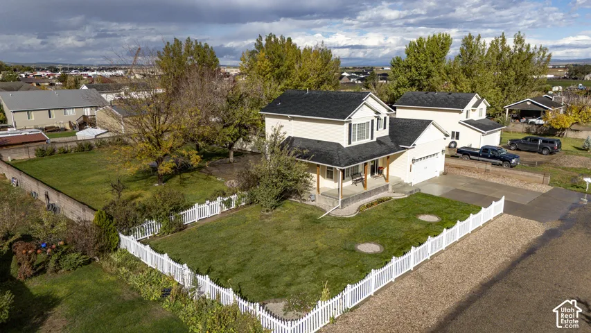 Two-story residence featuring a covered front porch, asphalt shingle roof, expansive fenced yard, and attached garage