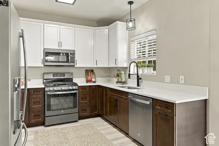 Kitchen featuring two-tone cabinetry with white upper and dark wood lower units, white stone-finish countertops, stainless steel appliances, and matte black hardware