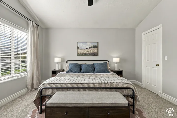 Neutral-toned interior featuring vaulted ceilings, a large window with white horizontal blinds, and a single-panel interior door