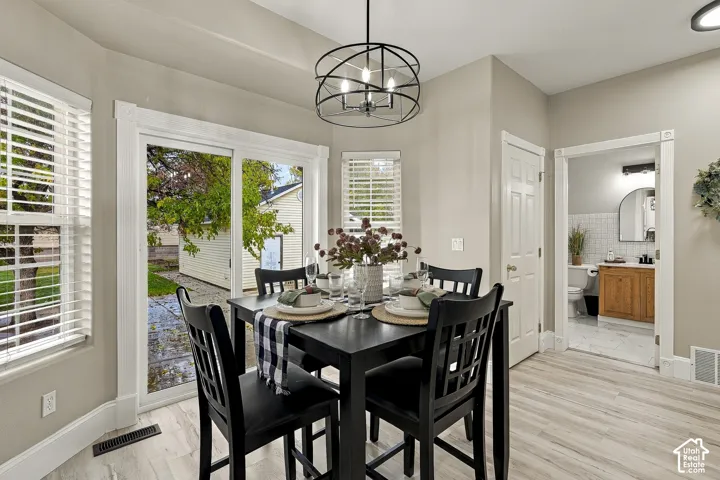 Dining area featuring wood-finish flooring, a geometric metal chandelier, and a sliding glass door providing exterior access