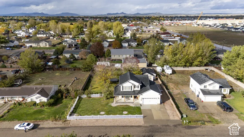 Two-story detached residence featuring a multi-gabled roofline, front porch with timber-post accents, attached garage, white picket fencing, and expansive grounds