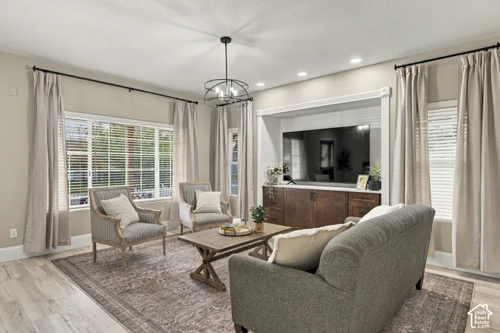 Living area featuring wood-finish flooring, a built-in media center with cabinetry, recessed lighting, and a multi-light metal chandelier