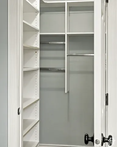 Walk-in closet featuring white built-in shelving, adjustable shelf tracks, and metal garment rods