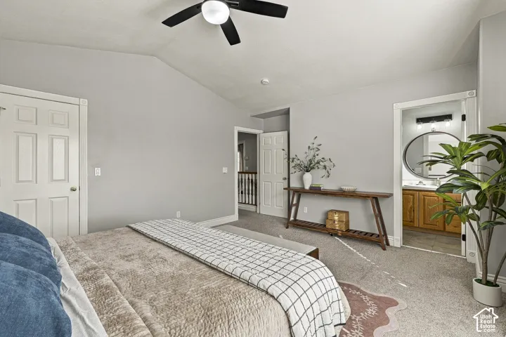 Vaulted ceiling with a matte black integrated ceiling fan, neutral wall tones, carpeted flooring, and six-panel interior doors