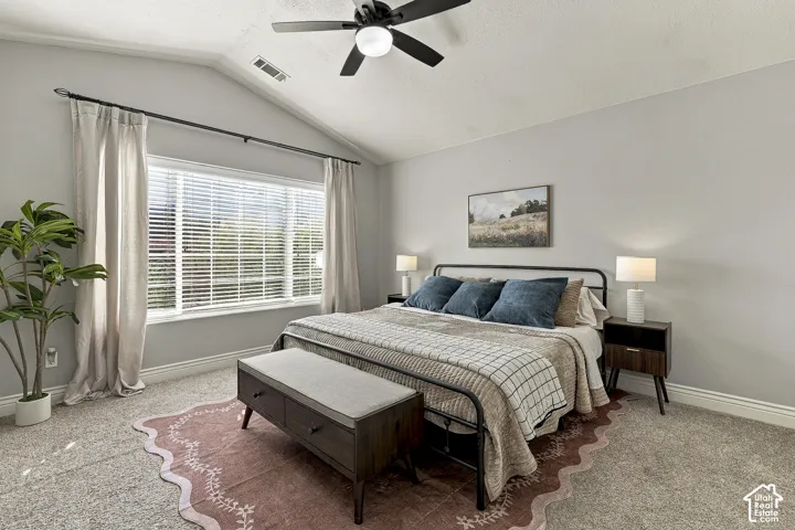 Vaulted ceilings featuring a central matte black ceiling fan and large window with dark metal curtain rod