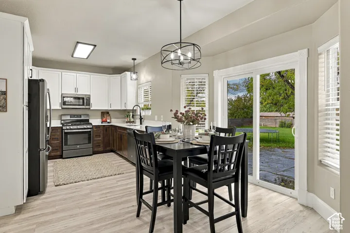 Kitchen featuring white upper cabinetry, dark wood lower cabinetry, stainless steel appliances, wood-finish flooring, and sliding glass doors