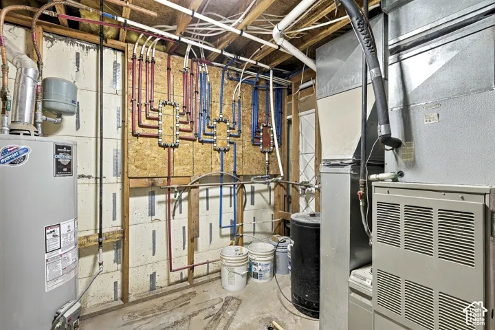 Mechanical utility space featuring a dedicated water heater, an HVAC system, and a multi-port water distribution manifold system mounted to an exposed stud wall