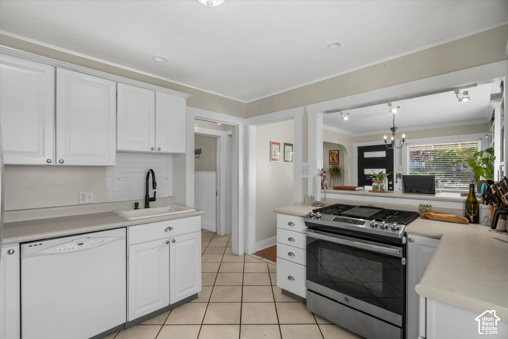 Kitchen featuring white cabinetry, solid-surface countertops, subway tile backsplash, stainless steel gas range, and ceramic tile flooring