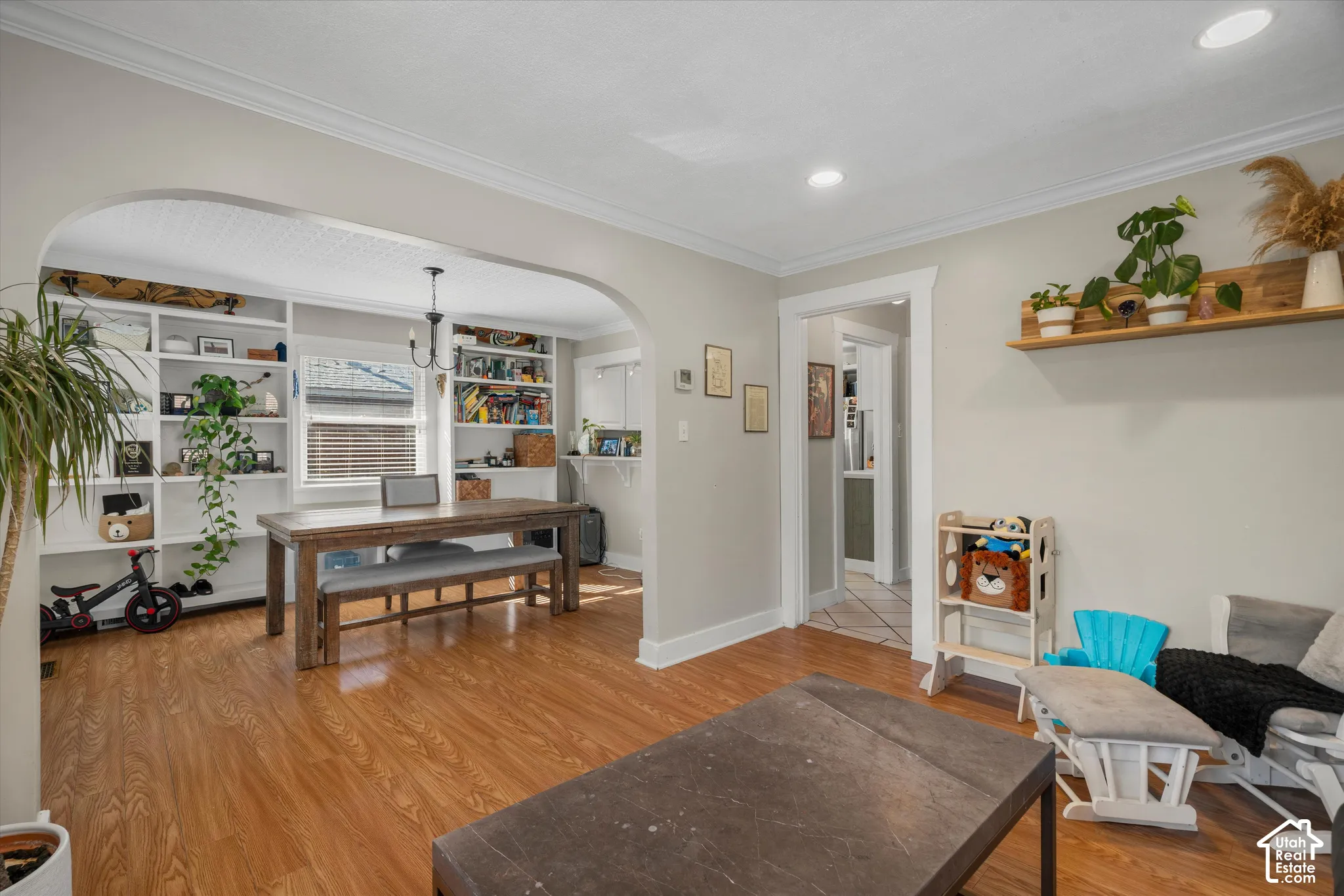 Interior room featuring wood-finish flooring, an arched entryway, recessed ceiling lighting, and floor-to-ceiling built-in cabinetry with integrated shelving