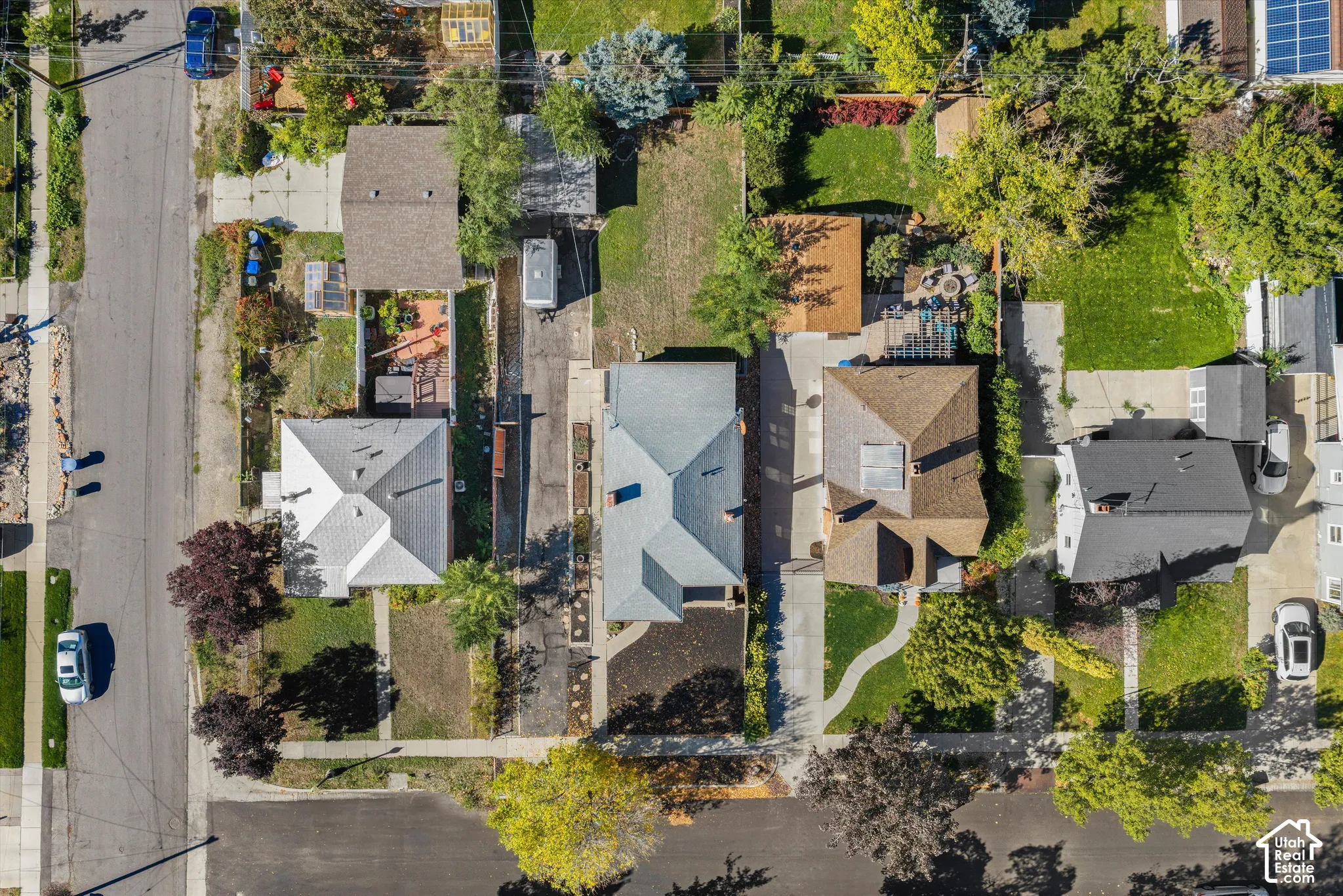 Aerial perspective featuring multiple residential lots with paved driveways, detached structures, and established landscaping
