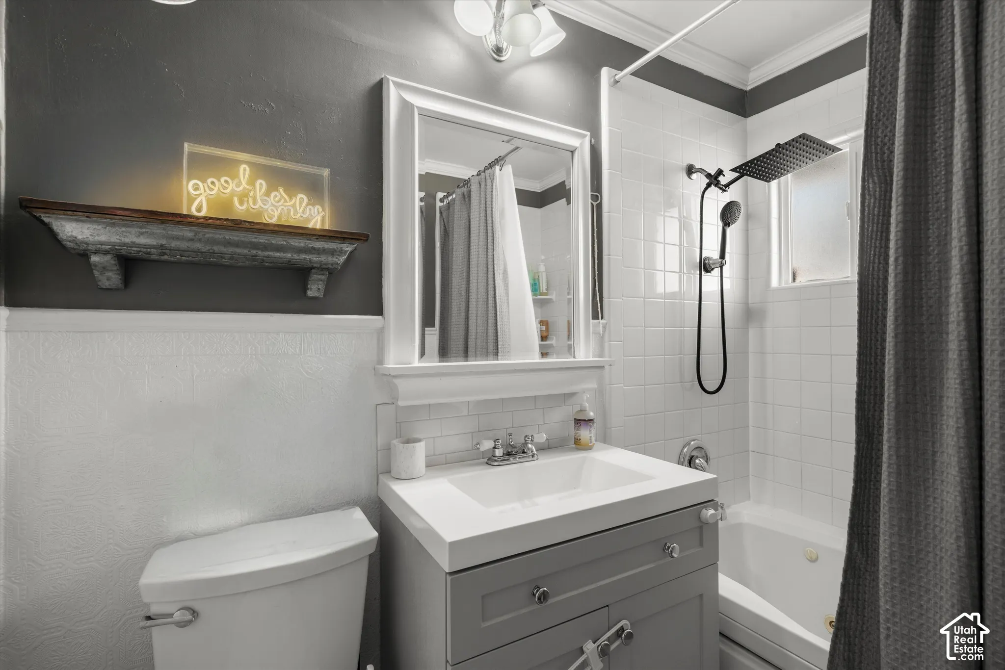 Bathroom featuring a gray vanity with an integrated rectangular sink, white subway tile backsplash, white tile tub surround, and a matte black rainfall showerhead