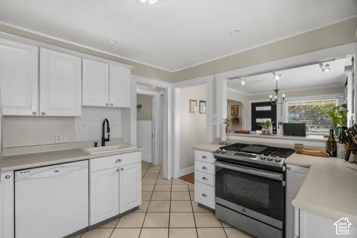 Kitchen featuring white cabinetry, solid-surface countertops, subway tile backsplash, stainless steel gas range, and ceramic tile flooring