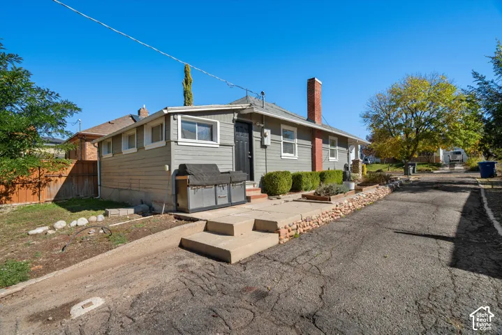 Exterior of the residence featuring horizontal siding, a red brick chimney, concrete steps, and a stone retaining wall