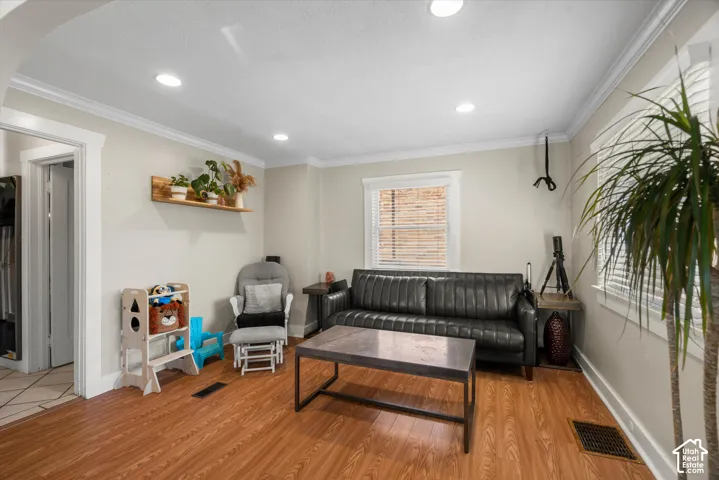 Wood-finish flooring, recessed lighting, crown molding, and wall-mounted shelving