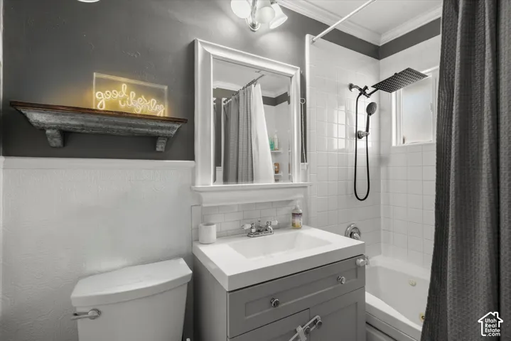 Bathroom featuring a gray vanity with an integrated rectangular sink, white subway tile backsplash, white tile tub surround, and a matte black rainfall showerhead