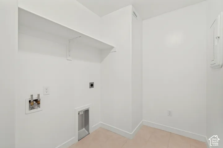 Utility area featuring built-in shelving, tiled flooring, plumbing hookups, and a recessed dryer vent box