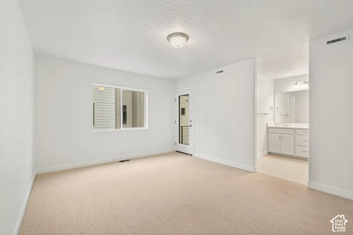 Neutral-toned wall-to-wall carpeting, single-pane window, exterior door with glass insert, and built-in vanity with attached vanity mirror and light fixture