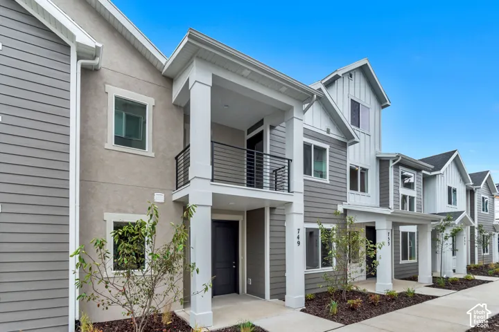 Exterior facade featuring mixed siding materials, covered entryways, second-story balconies with metal railings, and column supports