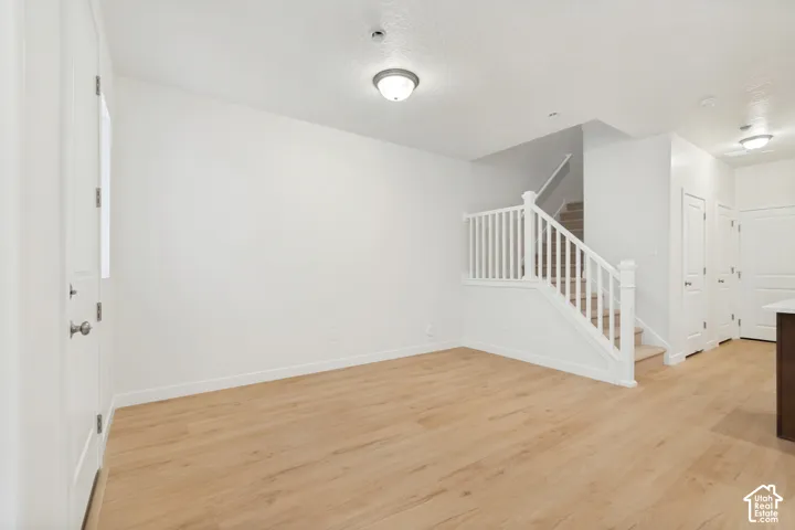 Wood-finish flooring, white paneled interior doors, and a staircase with a white wooden railing and balusters