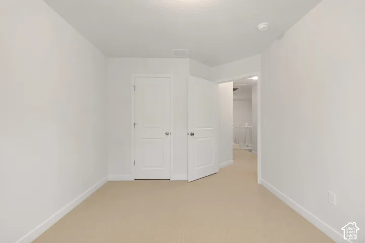 Interior room featuring neutral-toned carpeting, two-panel interior doors, and crisp white wall finishes