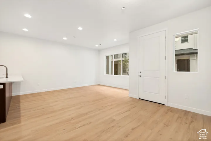 Interior space featuring wood-finish flooring, recessed lighting, multi-panel door, and white solid-surface countertop with undermount sink