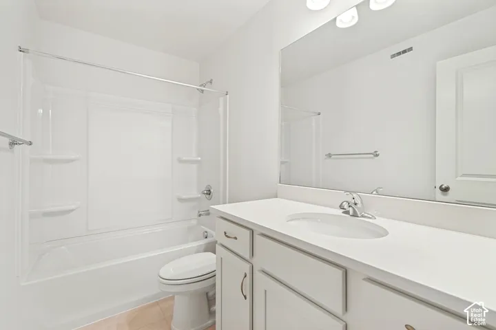 Bathroom featuring a tub-shower combination with integrated shelving, vanity with a solid surface countertop, an undermount sink, and a full-width wall mirror