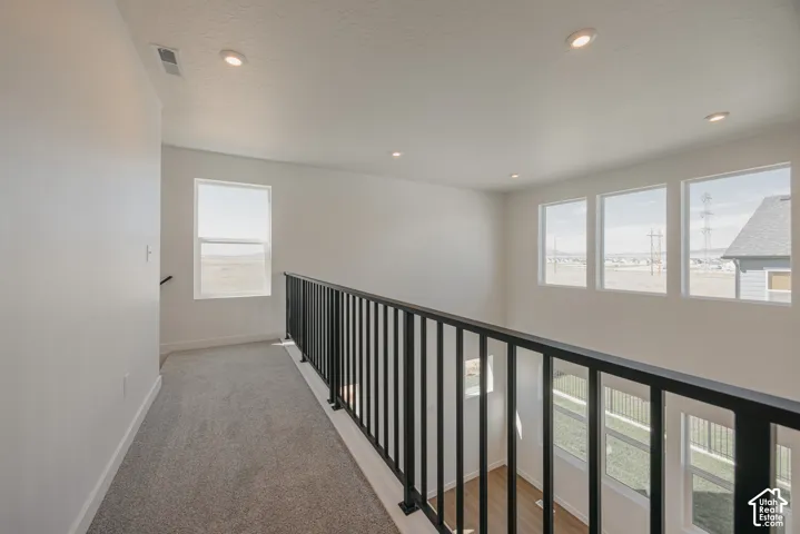 Open landing featuring wall-to-wall carpeting, black metal baluster railing, recessed lighting, and expansive windows