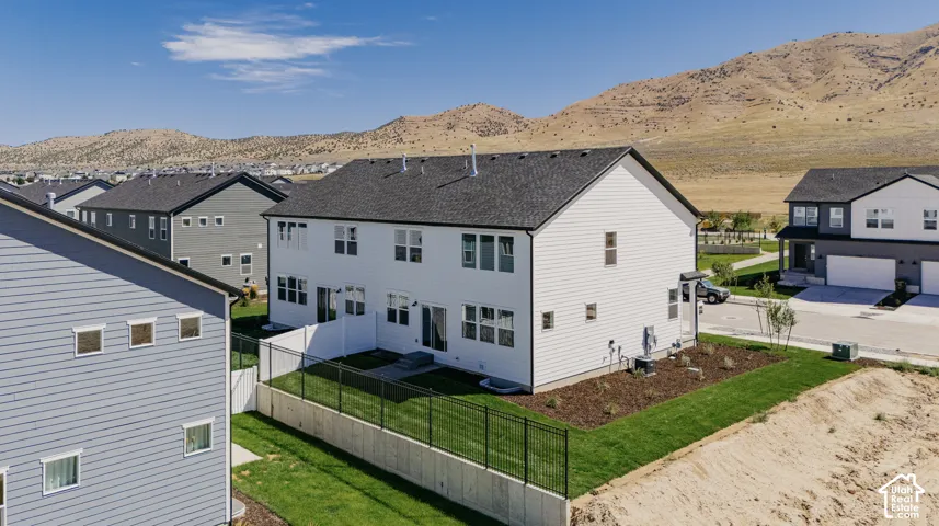 Two-story residence featuring white horizontal siding, an asphalt shingle roof, a fenced backyard, and mountain scenery
