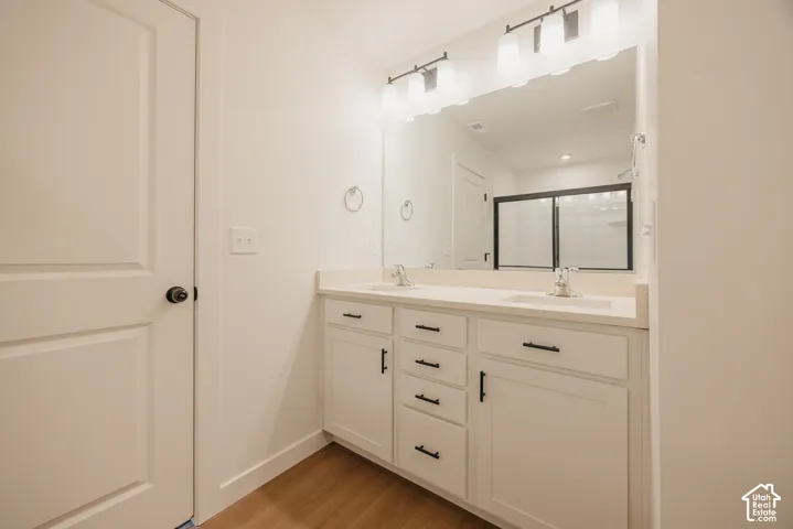 Dual-sink vanity with white cabinetry, stone-surface countertop, matte black hardware, and an expansive wall-mounted mirror