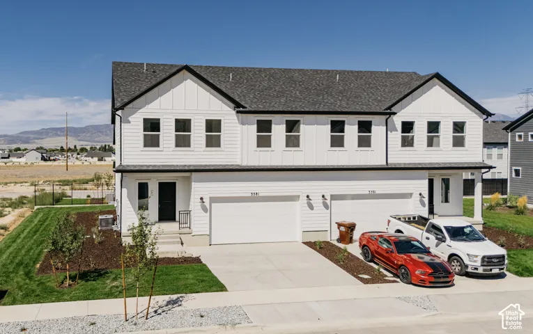 Two-story residence featuring white horizontal and vertical siding, a dark shingled roof, attached two-car garages, and concrete driveways