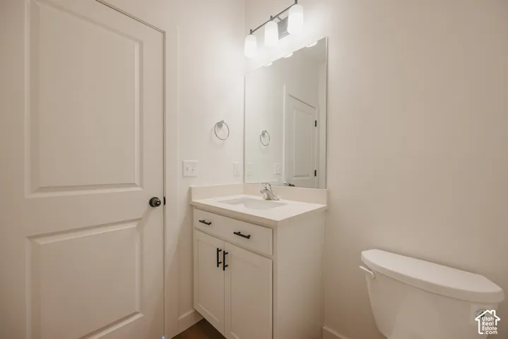 Bathroom featuring a white vanity cabinet with matte black hardware, a solid surface countertop with an integrated sink, a large frameless mirror, and a multi-bulb light fixture