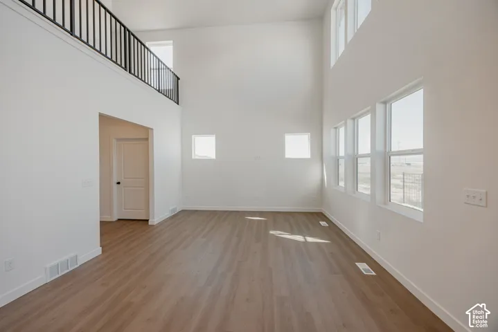 High-ceiling interior featuring wood-finish flooring, metal railing, and multiple large windows