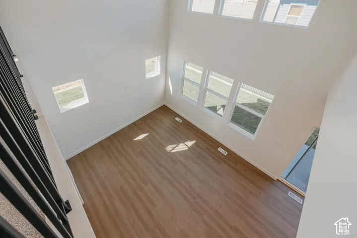 Double-height ceiling, wood-finish flooring, multi-pane windows, and black metal railing