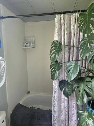 Bathtub surround featuring integrated corner shelving and a matte black shower rod