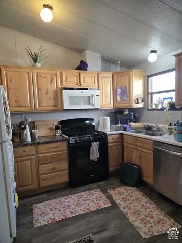 Kitchen featuring wood cabinetry, laminate countertops, a double-basin sink, and wood-finish flooring