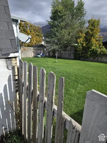 Backyard featuring a grass lawn, wood fencing, and mountain scenery