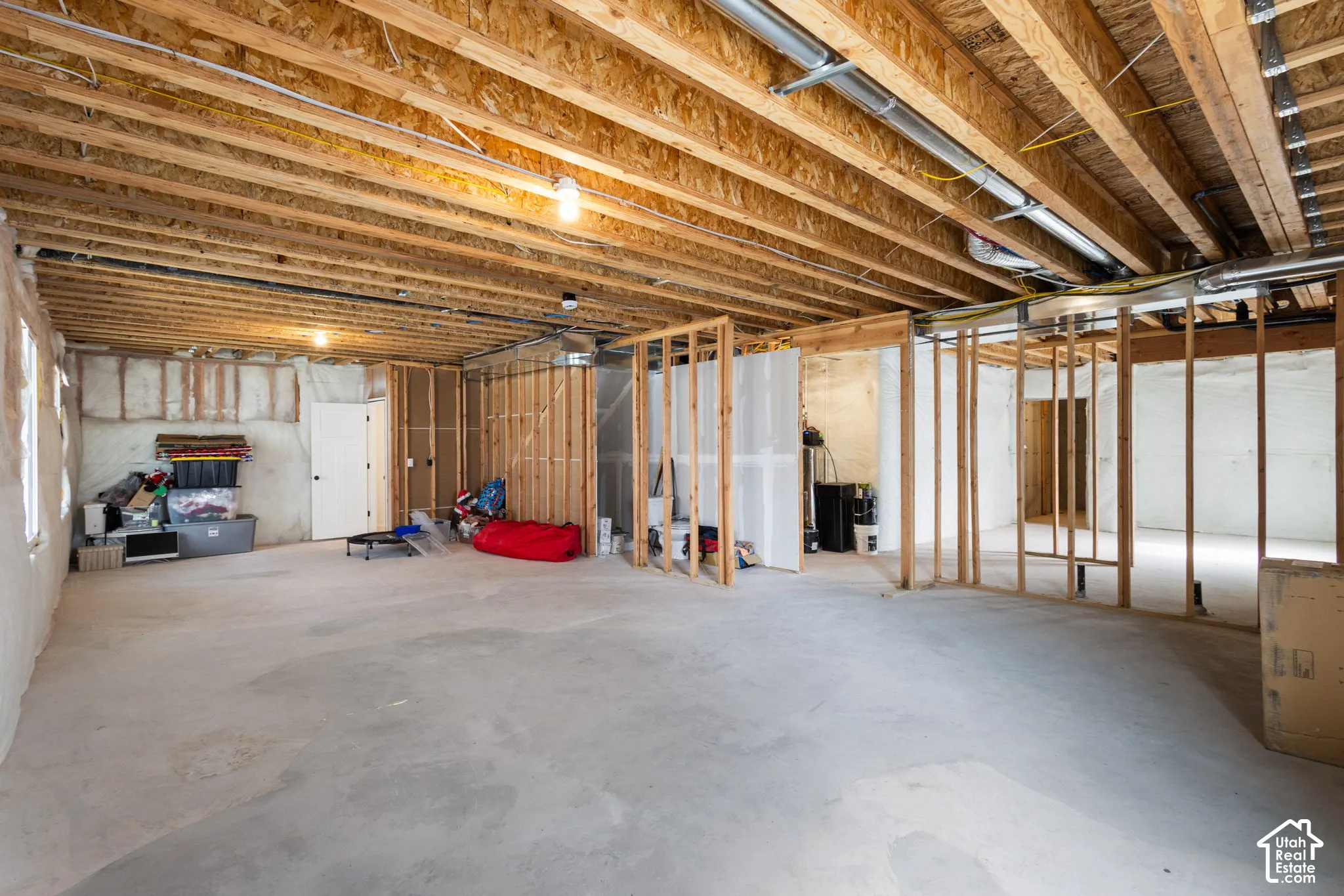 Unfinished lower level featuring exposed wood-joist ceiling, spray foam wall insulation, concrete flooring, and timber-frame partition walls