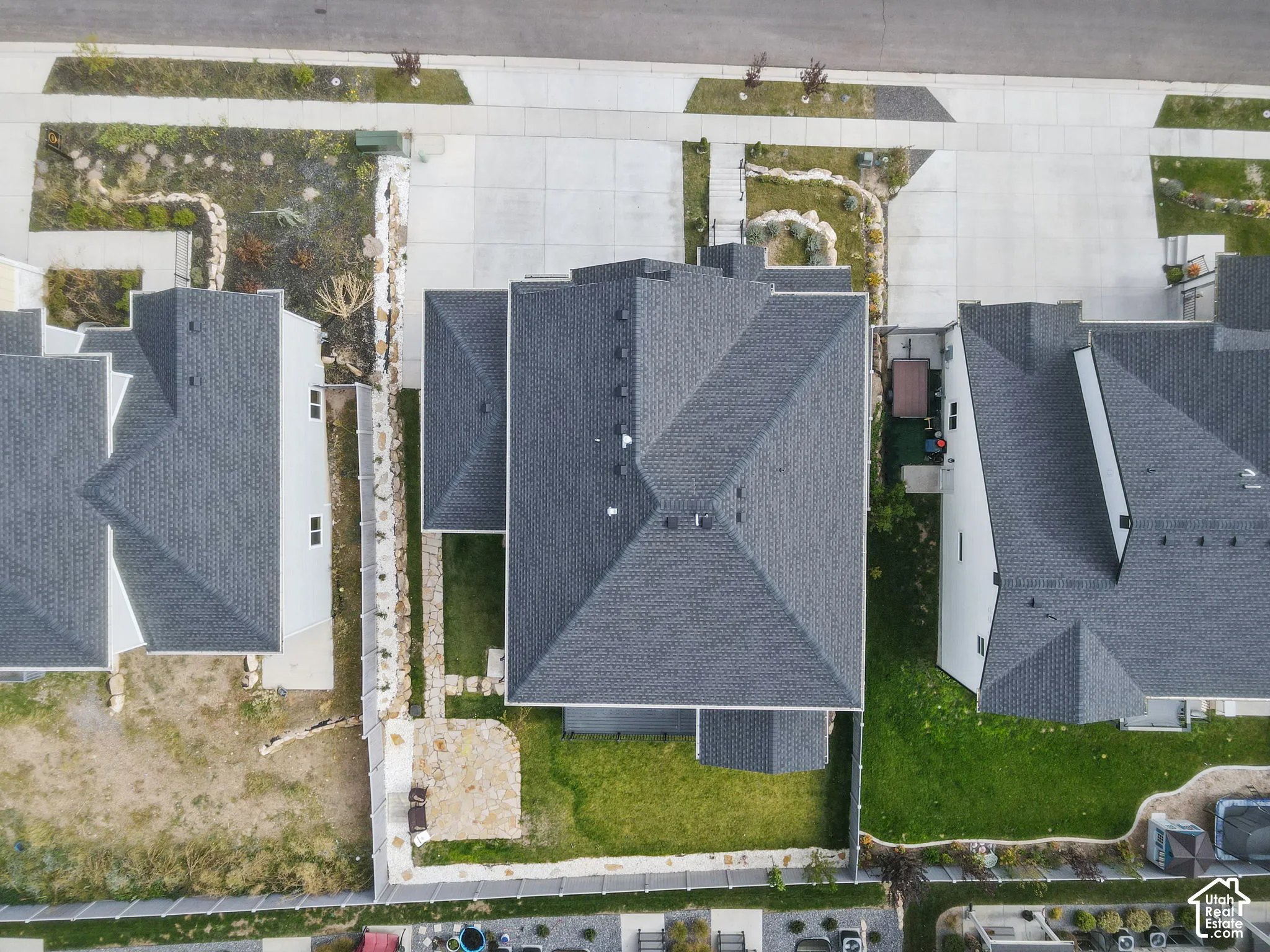 Aerial perspective featuring a multi-pitched asphalt shingle roof, a fenced backyard, and a paved stone patio area