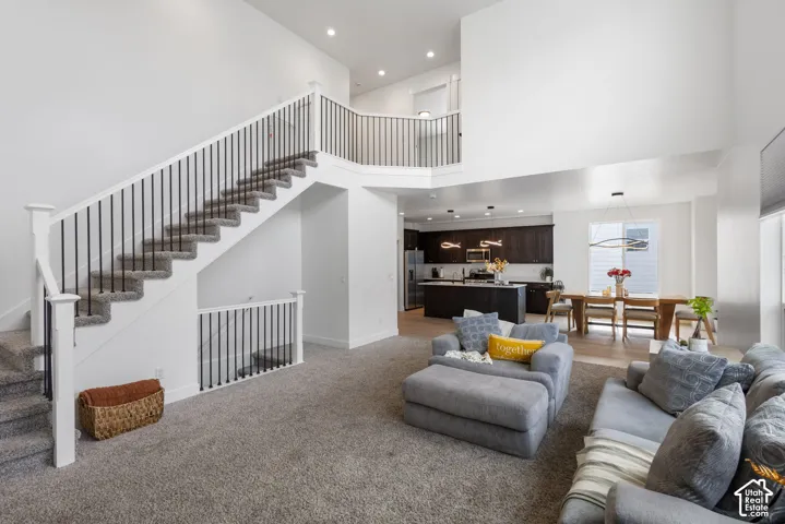 High ceilings, staircase with white railings and thin black balusters, recessed lighting, and kitchen with dark-finish cabinetry and a central island