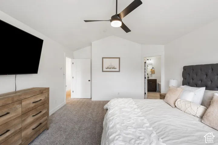 Vaulted ceilings, neutral carpeting, three-panel interior doors, and a matte black ceiling fan with integrated lighting