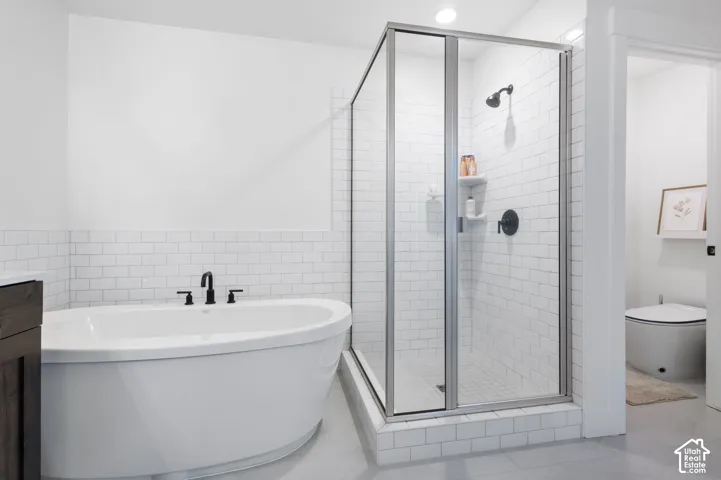 Freestanding soaking tub with matte black fixtures, glass-enclosed shower with subway tile surround, and integrated tile shelving