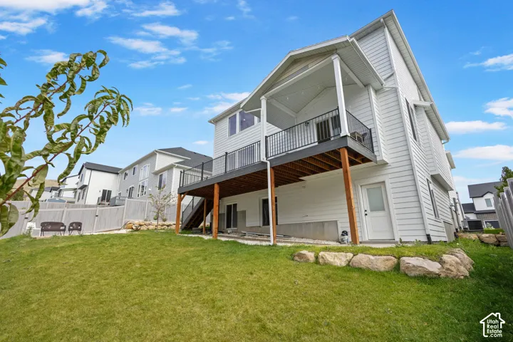 Two-story home with horizontal siding, elevated rear deck with metal railing, covered patio space, and tiered rock landscaping