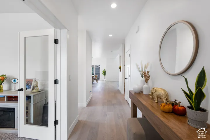 Hallway featuring wood-finish flooring, recessed lighting, and a white interior door with a glass pane
