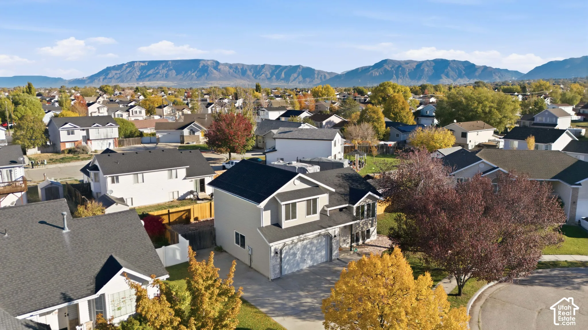 Two-story residence featuring a multi-gable roofline, attached two-car garage, concrete driveway, and mountain backdrop