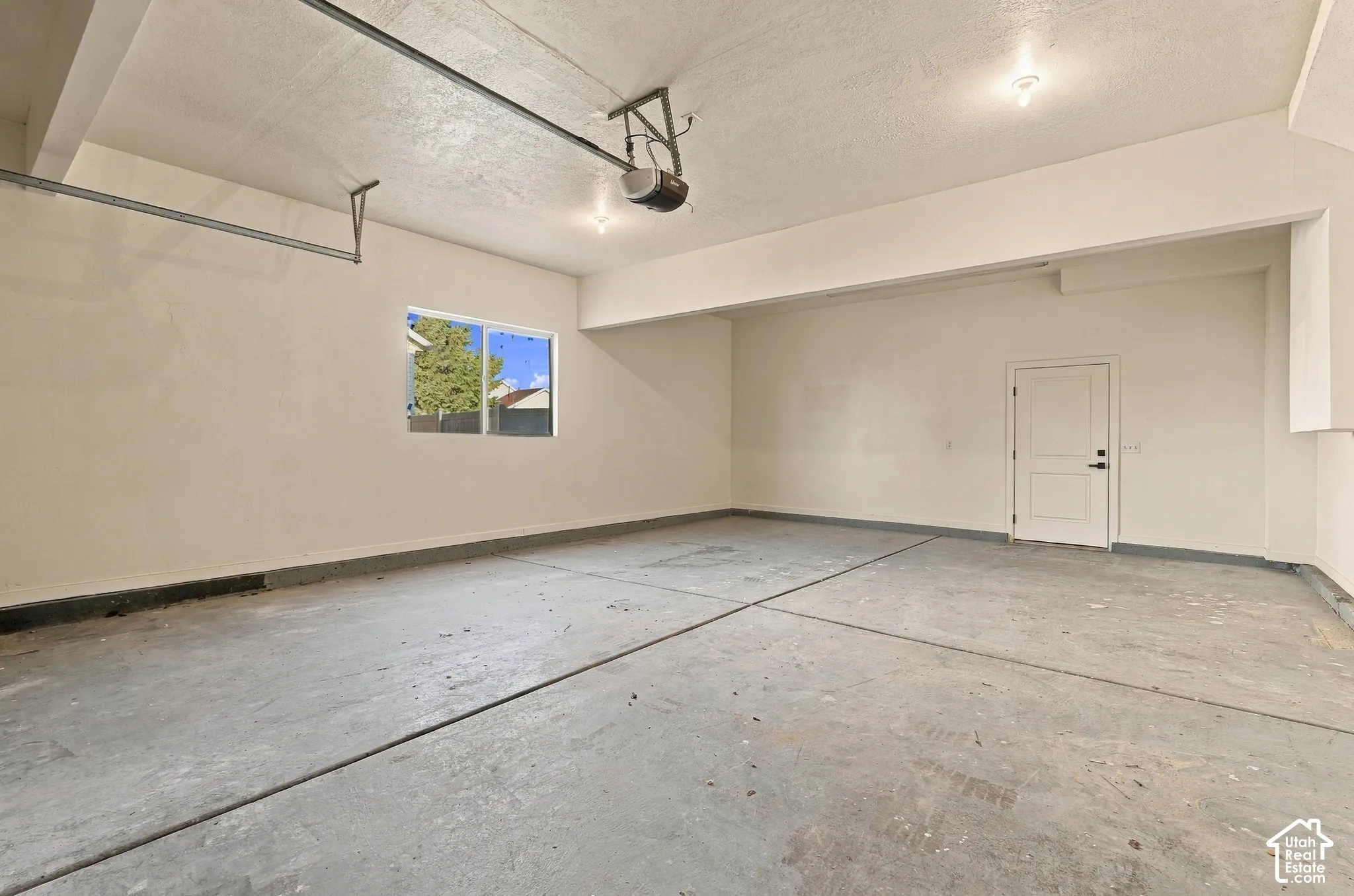 Garage space featuring a concrete floor, painted drywall, a single window, and a dedicated entry door