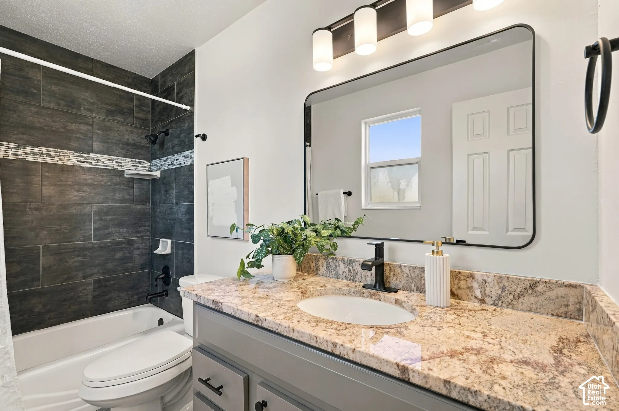 Bathroom featuring a vanity with stone-surfaced countertop, integrated oval sink, and matte black faucet